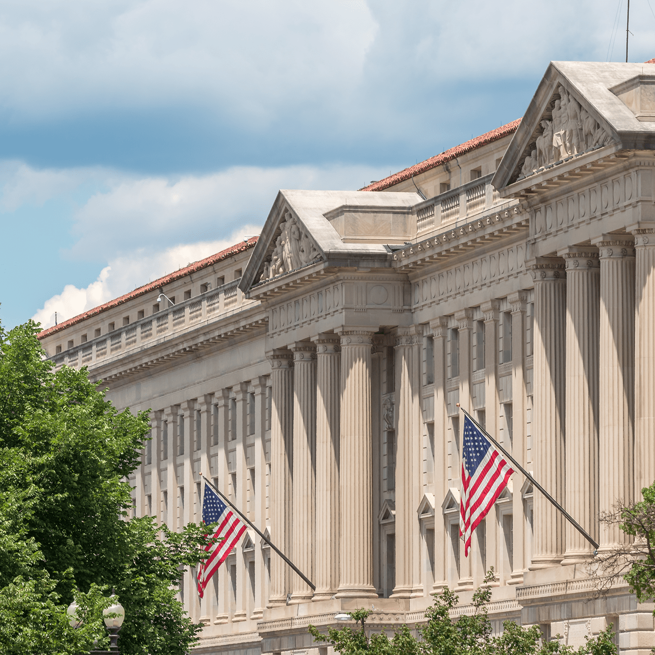 Historic building with American flags and trees.